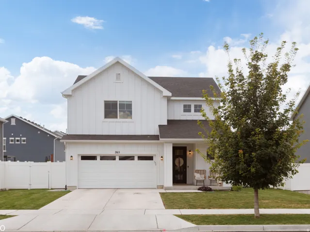 Two-story residence with white board and batten siding, dark shingle roof, and an attached two-car garage