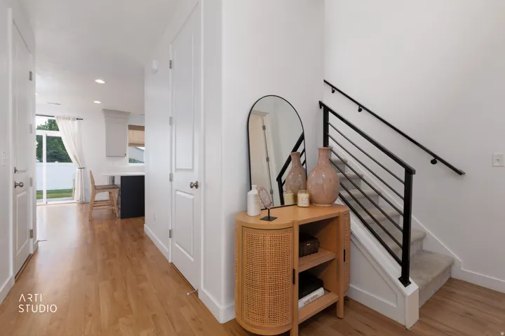 Wood-finish flooring, white walls, white doors, and a black metal staircase railing