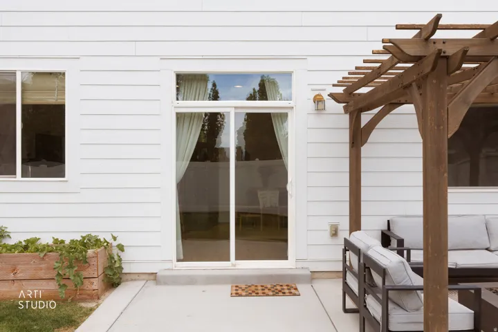 White horizontal siding with a sliding glass door and an attached wood pergola
