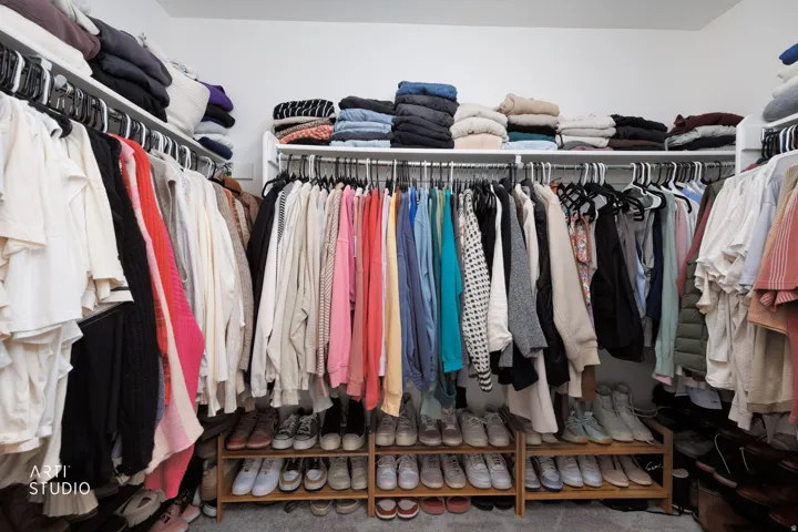 White wall paint with built-in shelving, multiple hanging rods, and wood-finish shoe storage