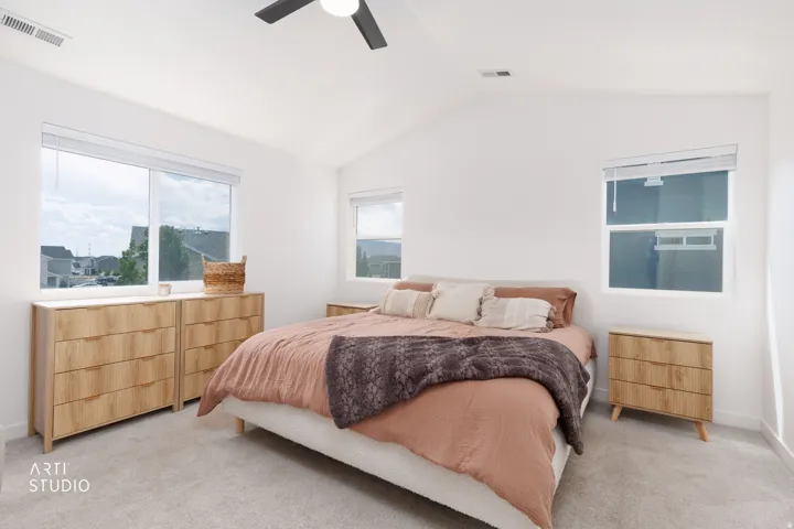 Vaulted ceiling room featuring light-colored carpeting, multiple windows, and a ceiling fan