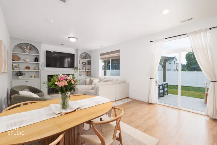 Built-in shelving flanking a fireplace, wood-finish flooring, recessed lighting, and a sliding glass door opening to a patio and fenced yard