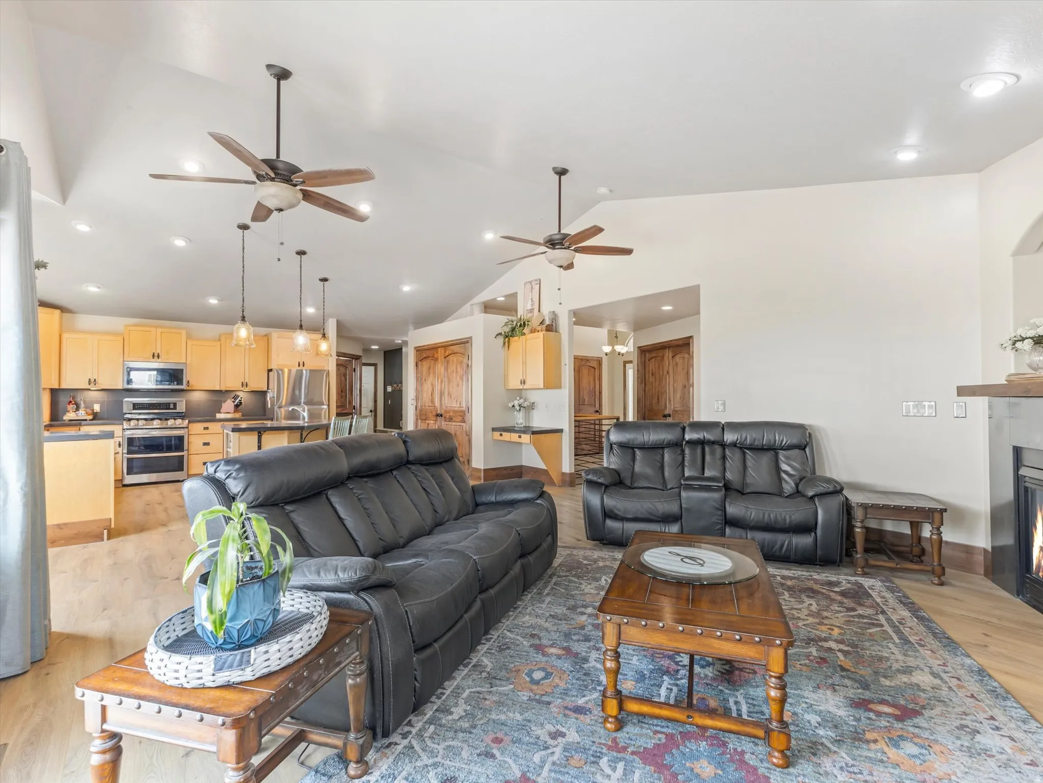 Open-concept living and kitchen area with wood-finish flooring throughout, recessed lighting, and ceiling fans