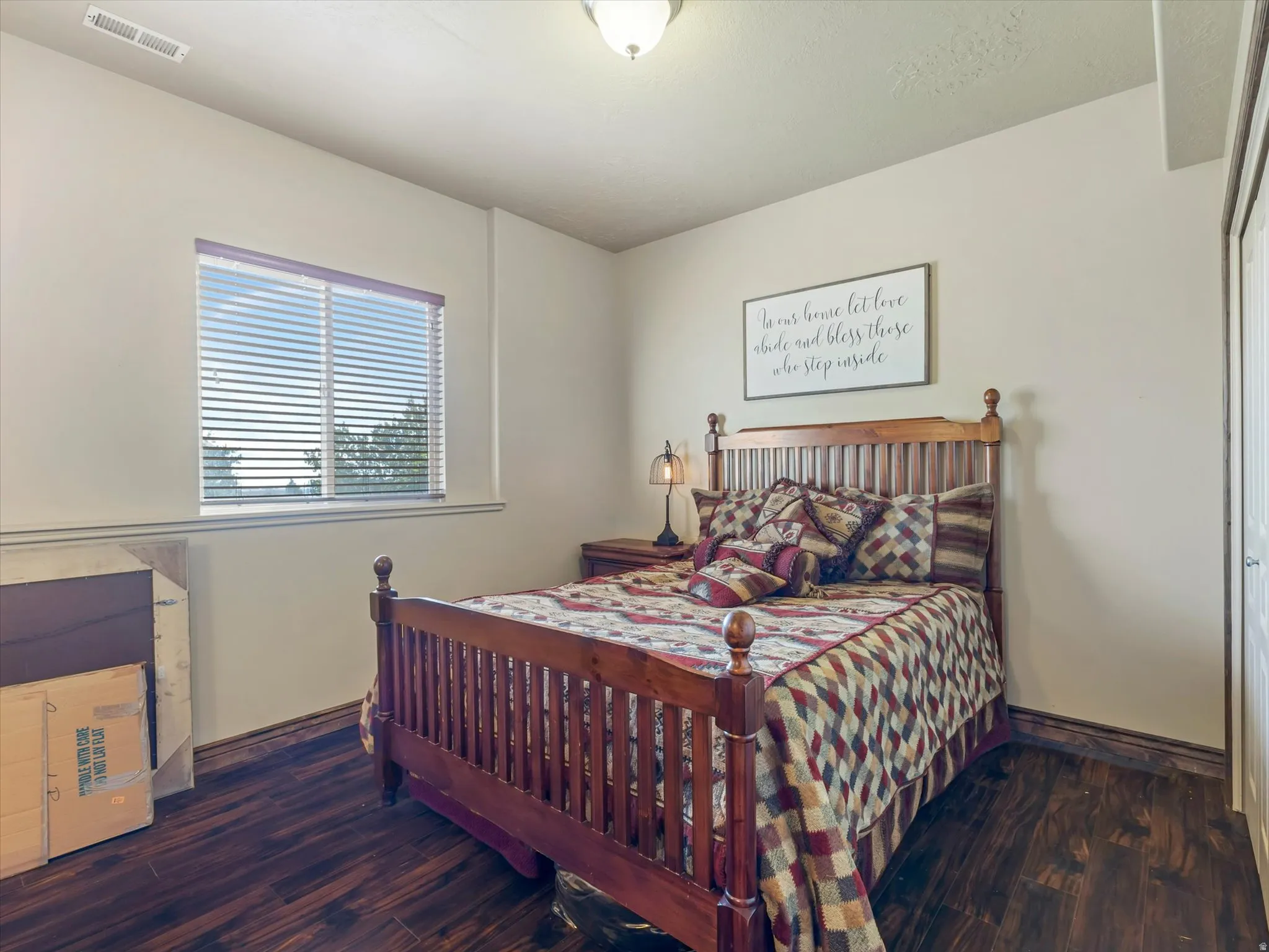Basement Bedroom 2 - Wood-finish flooring with coordinating wood trim, a ceiling-mounted light fixture, and a window with blinds