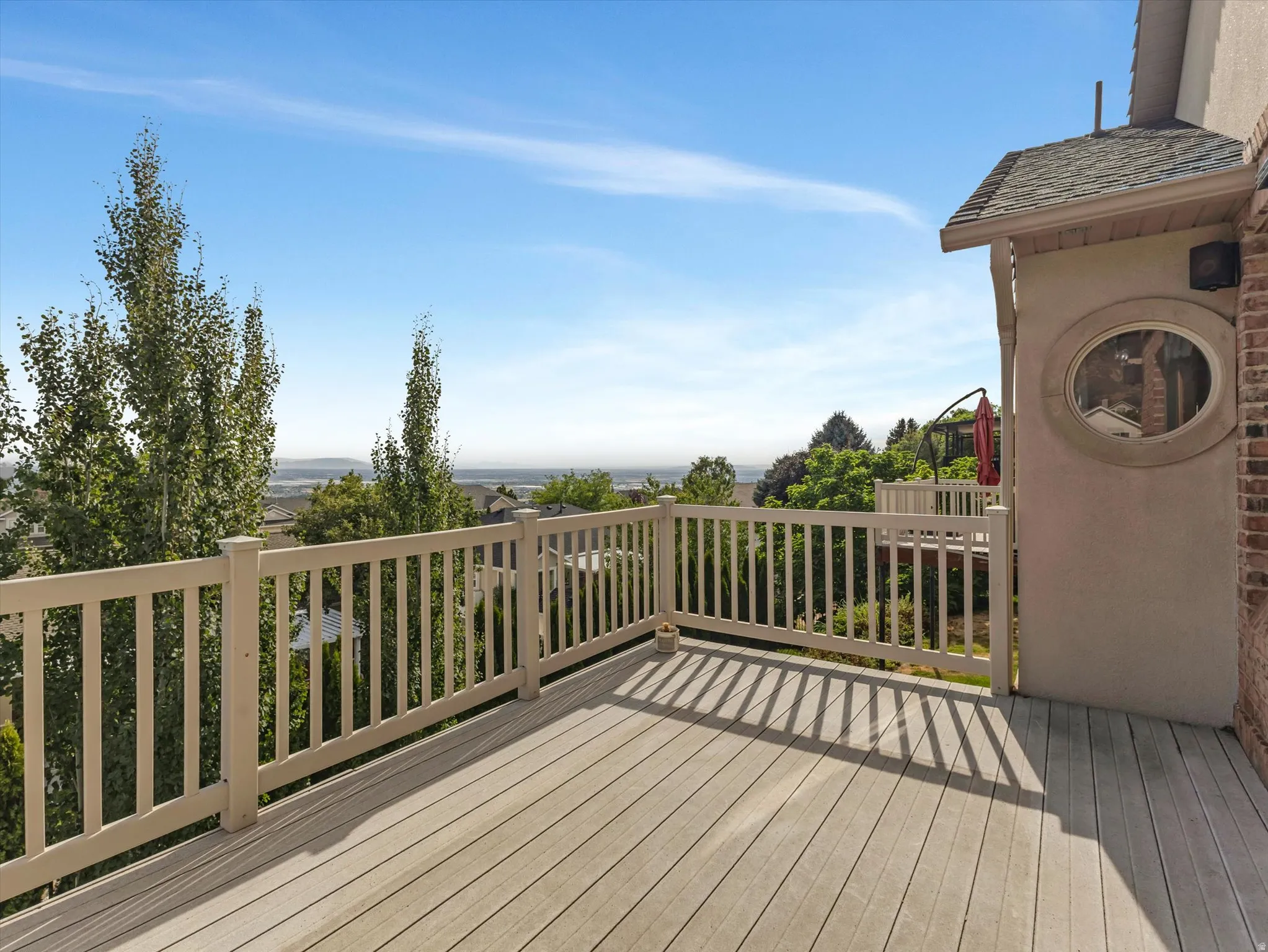 Amazing Views!  Deck off family room with composite wood-finish flooring and sturdy wood railing system, overlooking expansive grounds with mature poplar trees and distant landscape vistas