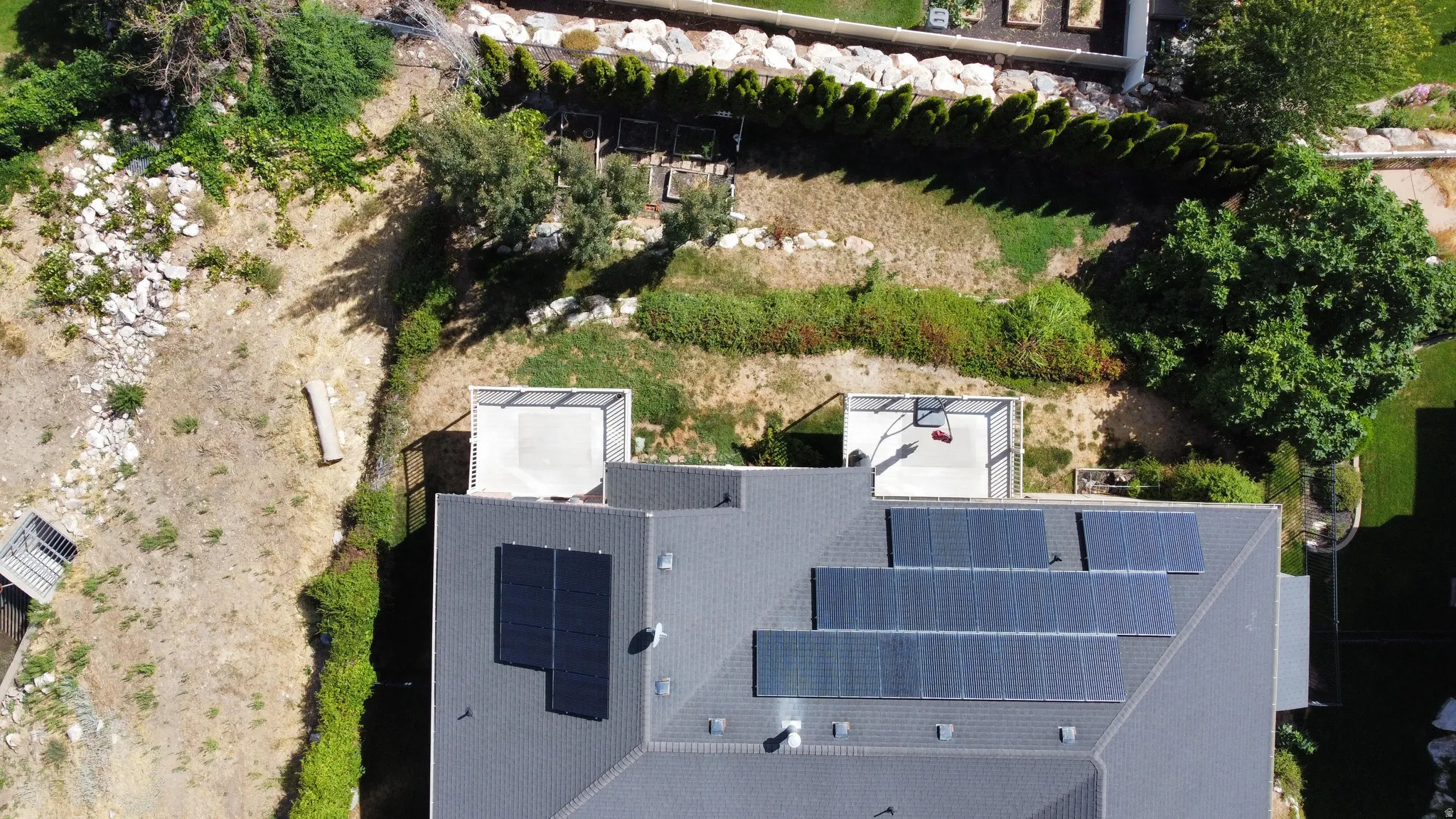 Birdseye view of backyard, neighboring vacant land, and solar panels.