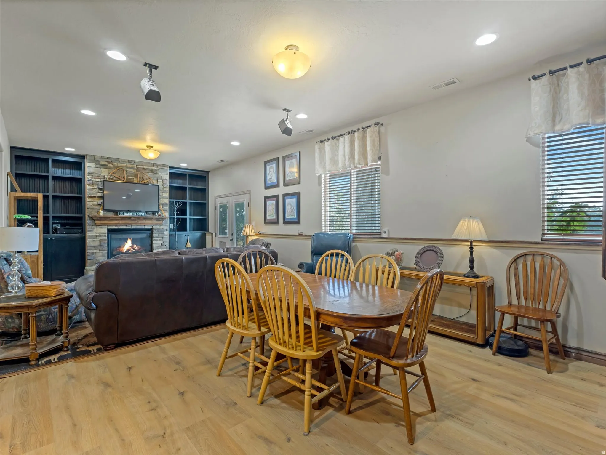 Living area featuring wood-finish flooring, a stone fireplace with a wood mantle, and built-in shelving