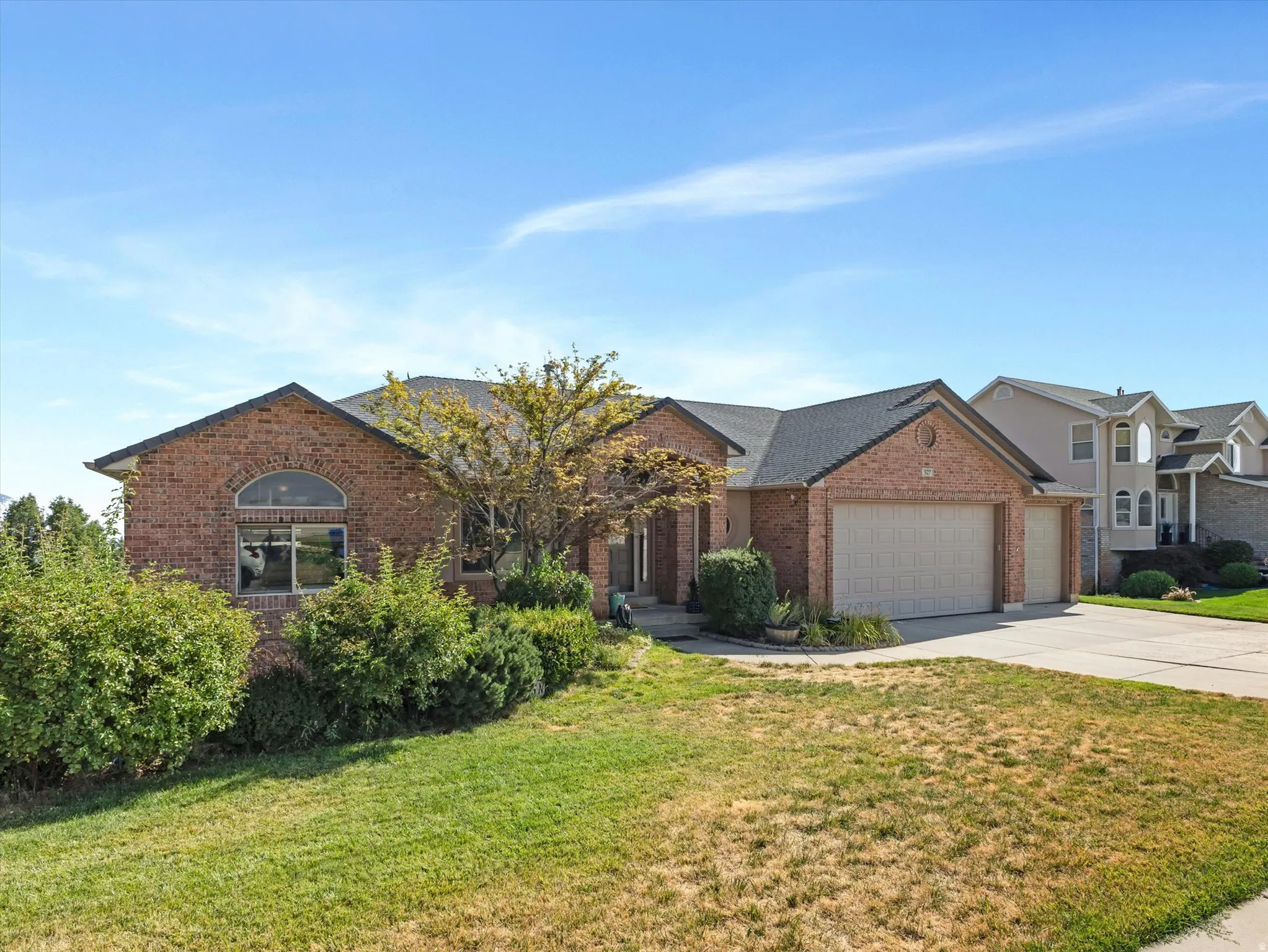 Brick exterior with a dark shingle roof, attached two-car garage, and established front landscaping