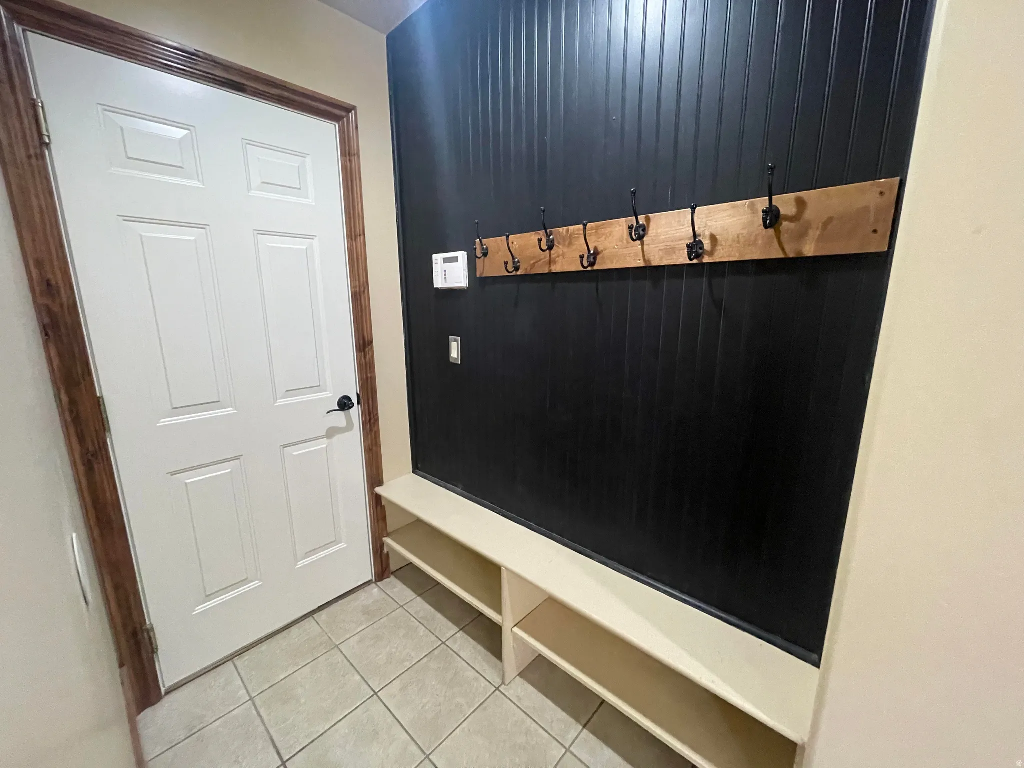Mud Room with Panel-style interior door with wood-finish trim leading to garage.