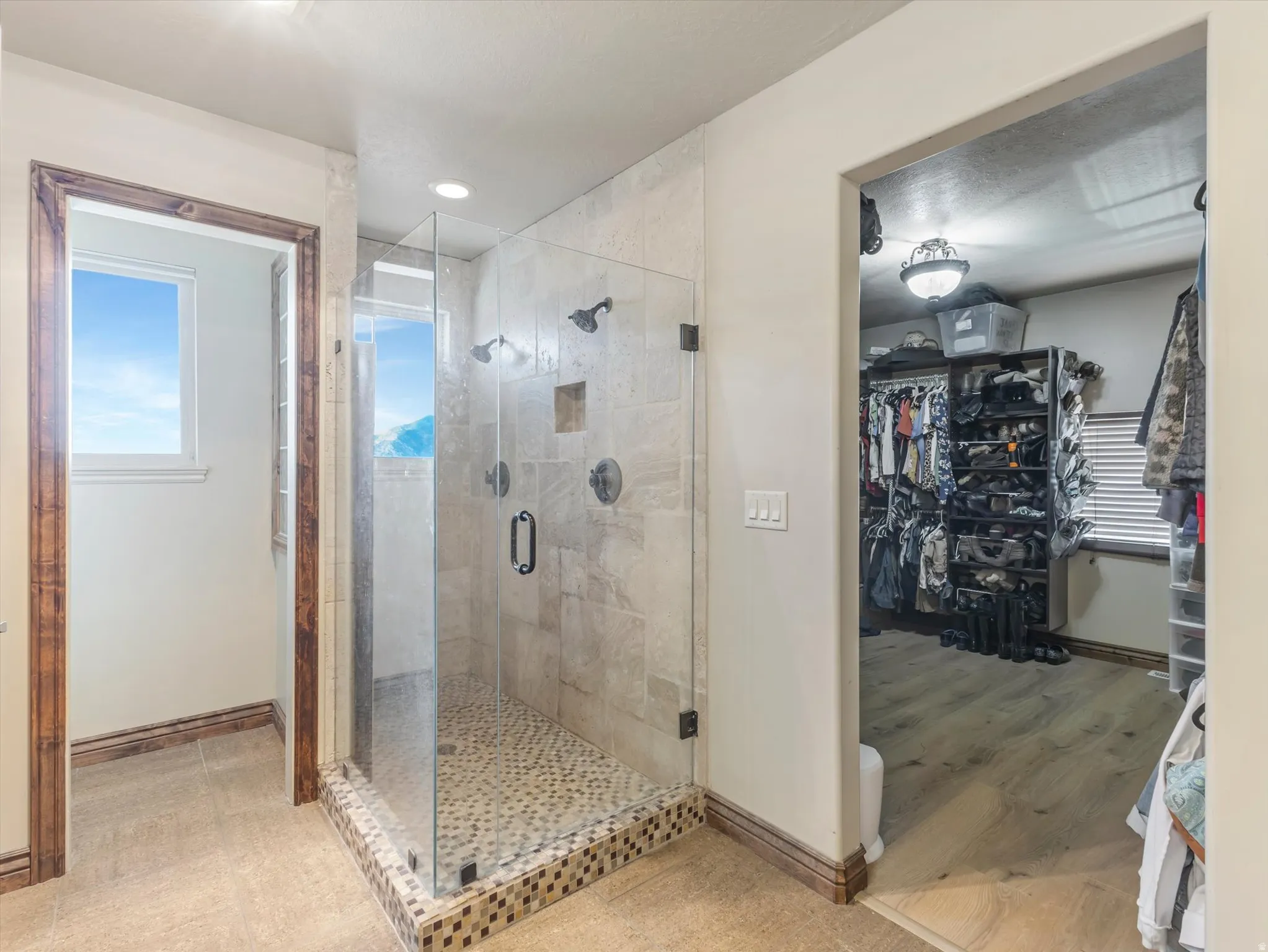 Master Bath Suite with Frameless Glass Shower Enclosure, Pebble Mosaic Shower Floor, Dual Shower Heads, and Direct Access to Walk-In Closet with Built-In Shelving and Organizational Systems