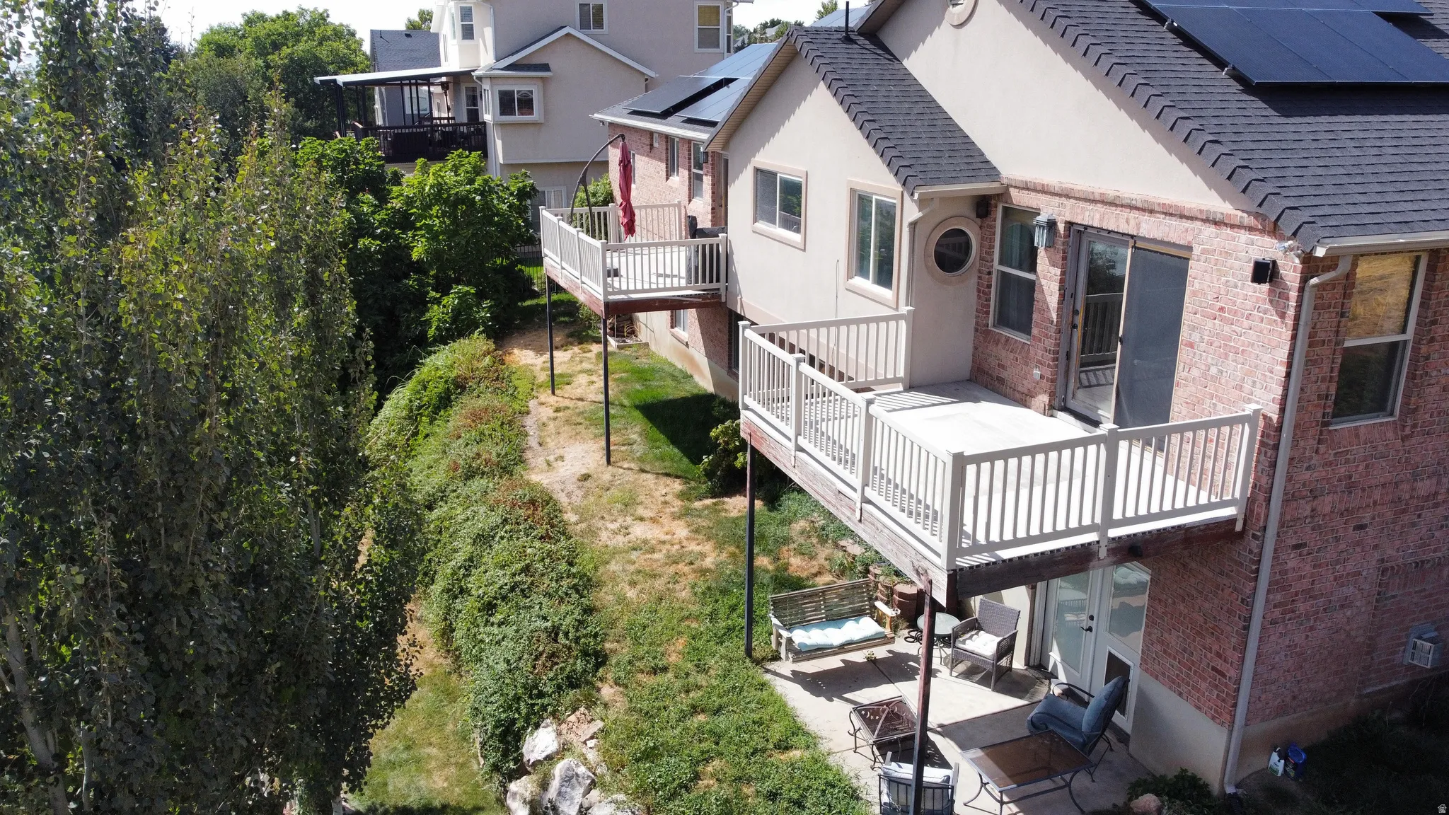 Exterior with brick siding, a multi-level deck, dark shingle roofing, and solar panels