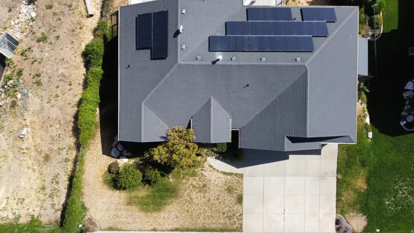 Birdseye view of front yard, neighboring vacant land, and solar panels.