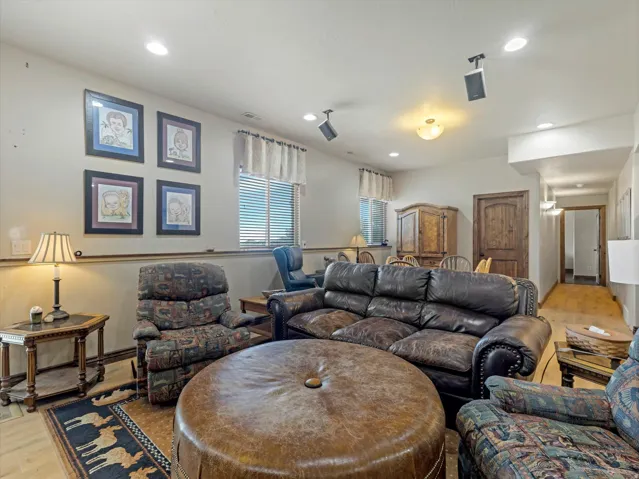 Spacious living room with recessed ceiling lighting, ceiling fan, and large windows with plantation shutters