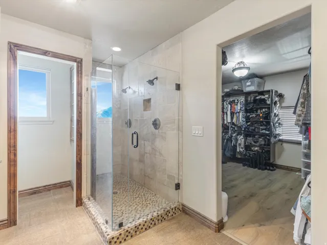 Master Bath Suite with Frameless Glass Shower Enclosure, Pebble Mosaic Shower Floor, Dual Shower Heads, and Direct Access to Walk-In Closet with Built-In Shelving and Organizational Systems