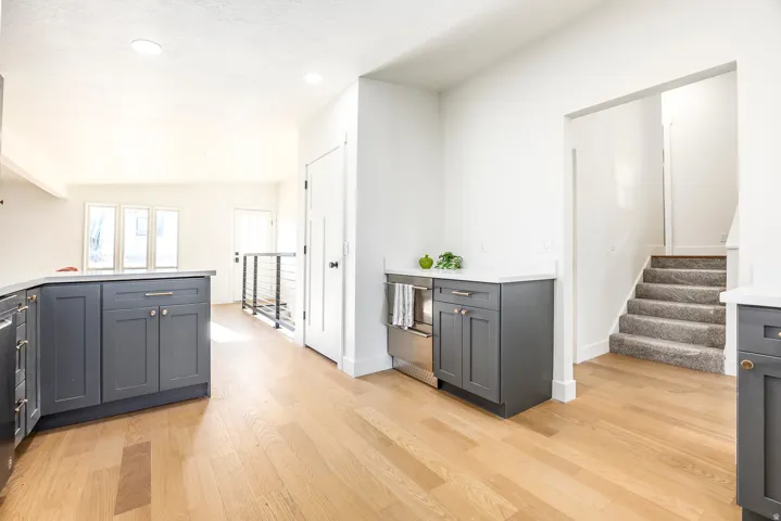 Contemporary kitchen with dark gray cabinetry, light wood-finish flooring, recessed lighting, and white countertops