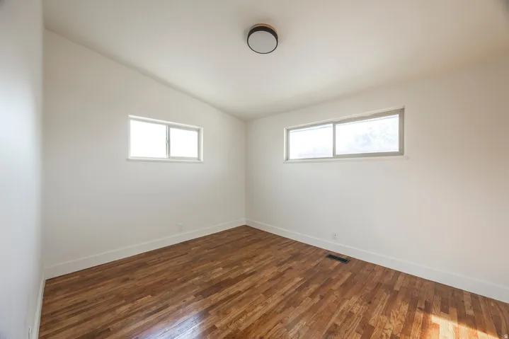 Hardwood flooring, two windows, recessed ceiling light fixture, white trim