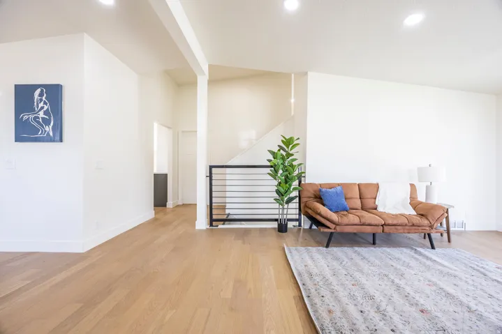 Open-concept living area featuring wood-finish flooring, recessed lighting, and a contemporary stair railing