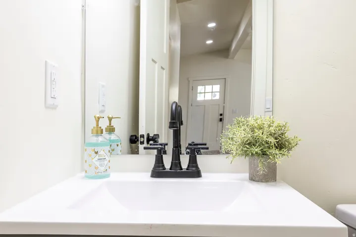 White integrated sink with a matte black faucet, wall-mounted mirror, and light-toned walls