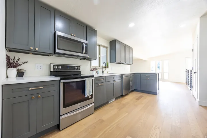 Kitchen featuring gray shaker-style cabinetry, stainless steel appliances, light-toned wood-finish flooring, white countertops, and recessed lighting
