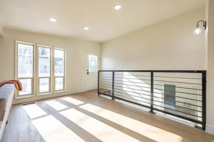 Light wood-finish flooring, recessed lighting, and a white interior door with glass paneling