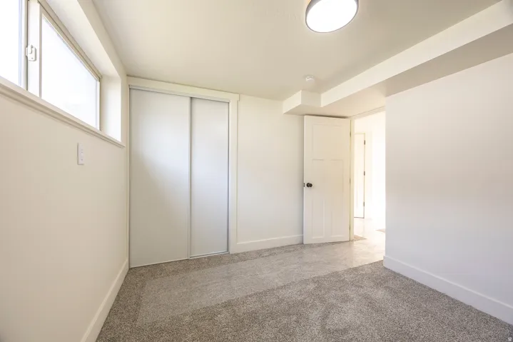 Recessed window, sliding closet doors, wall-mounted light fixture, carpeted flooring, and a paneled door