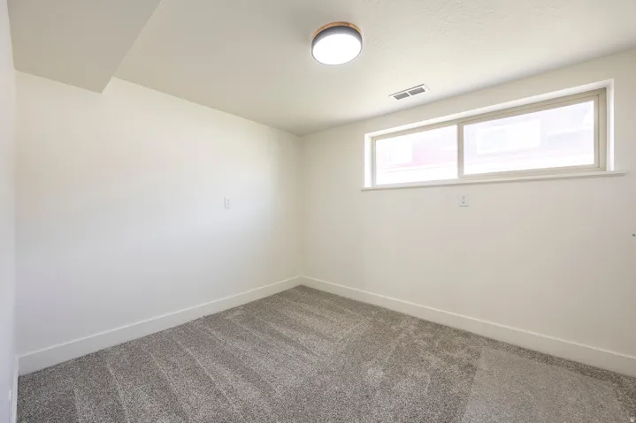 Neutral wall paint, gray carpet flooring, recessed ceiling with a flush-mount light fixture, and horizontal window