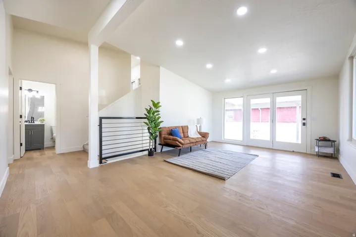 Open-concept living space with wood-finish flooring, recessed lighting, and a modern stair railing