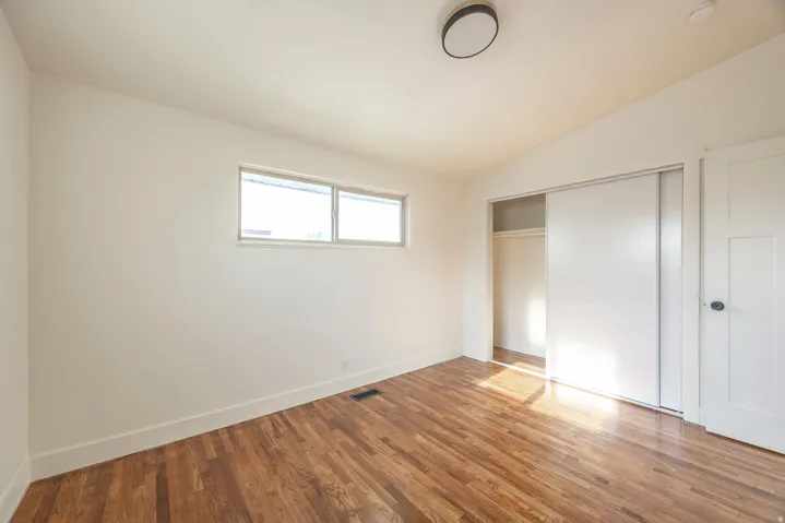 Wood-finish flooring, white walls, and a window with a white frame