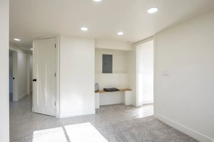 Recessed lighting illuminating the carpeted flooring and built-in wooden bench