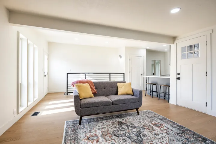 Recessed lighting illuminating wood-finish flooring, white walls, and a modern half-wall railing