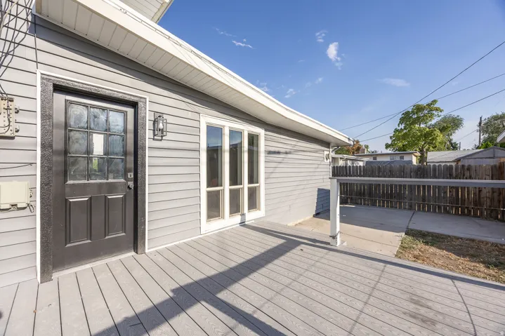 Grey composite decking with a dark wood fence and light grey siding