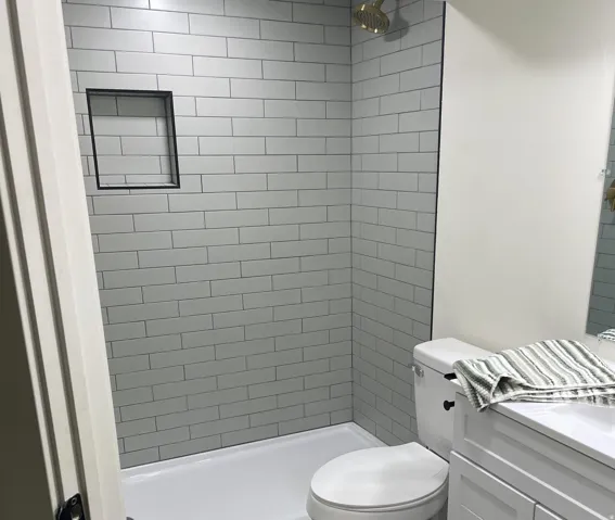 Shower with subway tile surround, built-in niche, and gold-finish showerhead