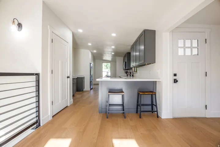 Recessed lighting, wood-finish flooring, white paneled doors, dark gray cabinetry, and a white countertop