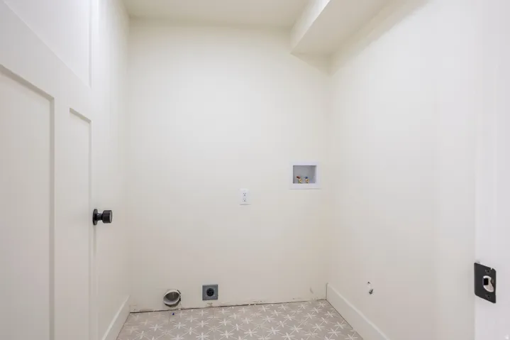 Bright utility space featuring patterned floor tile and a paneled door with matte black hardware