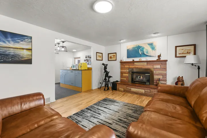 Spacious living area with hardwood floors, stone fireplace, and an open connection to the kitchen. and a brick fireplace with gas insert