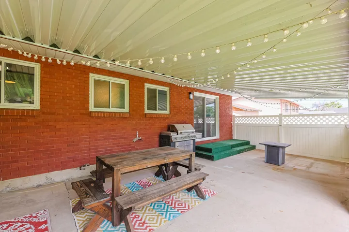 This expansive covered outdoor space overlooks the landscaped yard and offers a sheltered setting for outdoor dining, entertaining, and relaxation.