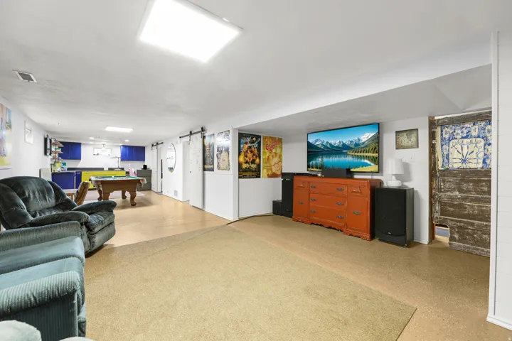 This expansive lower-level family room offers flexible space for relaxing and entertaining, with a comfortable seating area, game area, and distinctive fireplace.