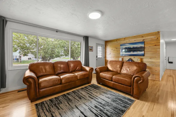Hardwood floors, a wood accent wall, and a large picture window create a bright, inviting gathering space.