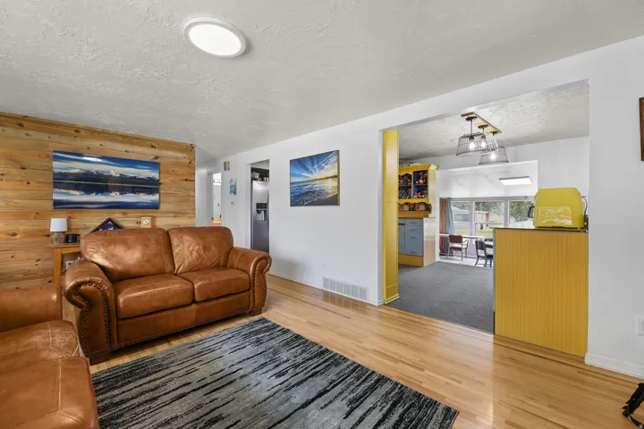 Hardwood flooring and a wood-paneled feature wall highlight the open flow toward the kitchen.