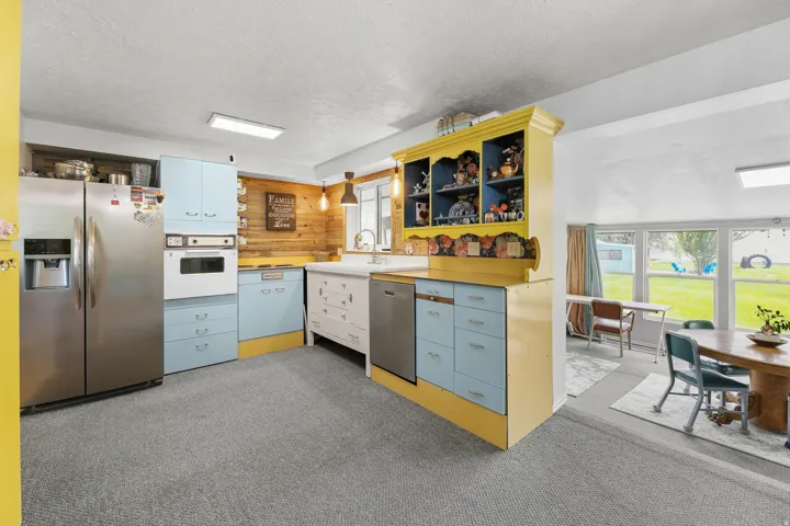 Light-blue cabinetry, yellow accents, stainless steel and mid-century modern appliances, create a bright, functional space.