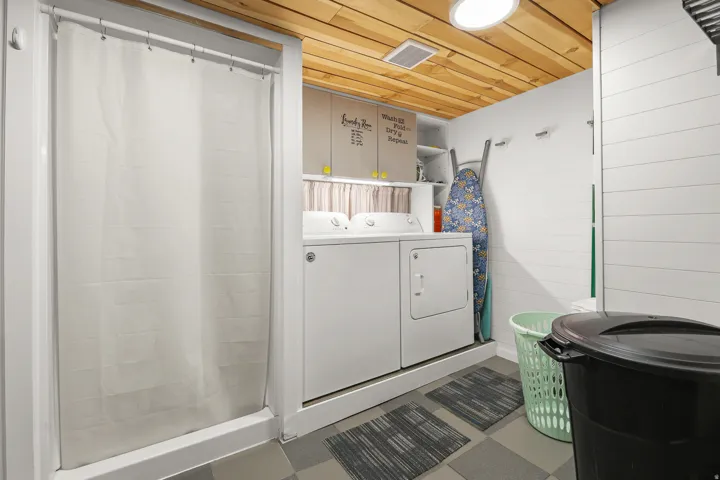 A practical laundry area includes a washer and dryer, utility sink, storage, and convenient built-in shelving.