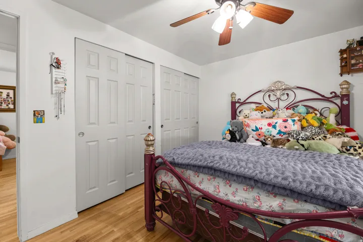 White walls, wood-finish flooring, and white two-panel sliding closet doors
