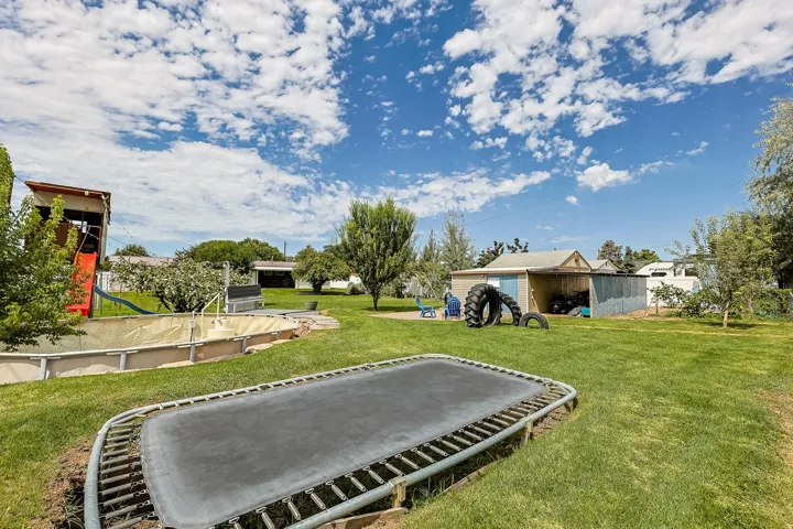 A large lawn, mature trees, and a built-in recreational feature provide multiple options for outdoor enjoyment and activities.