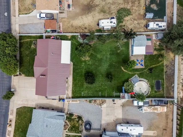 Aerial view showcasing a spacious residential lot with mature landscaping, manicured lawn, and established trees