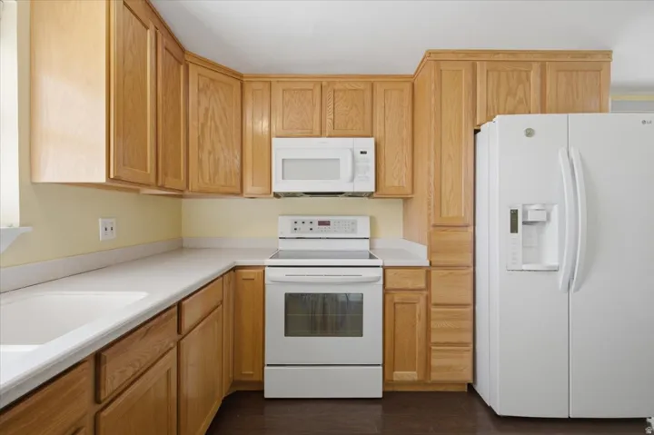 Light wood cabinetry with white countertops and integrated sink