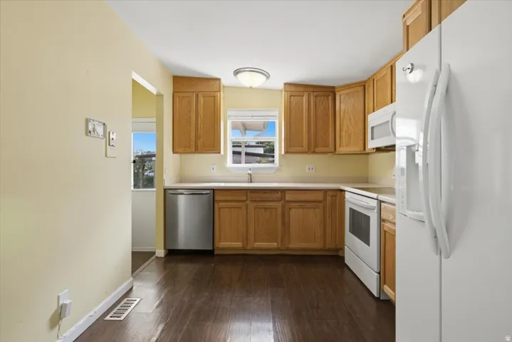 Kitchen featuring wood-finish flooring, wood cabinetry, light-toned countertops, a stainless steel dishwasher, and an electric range