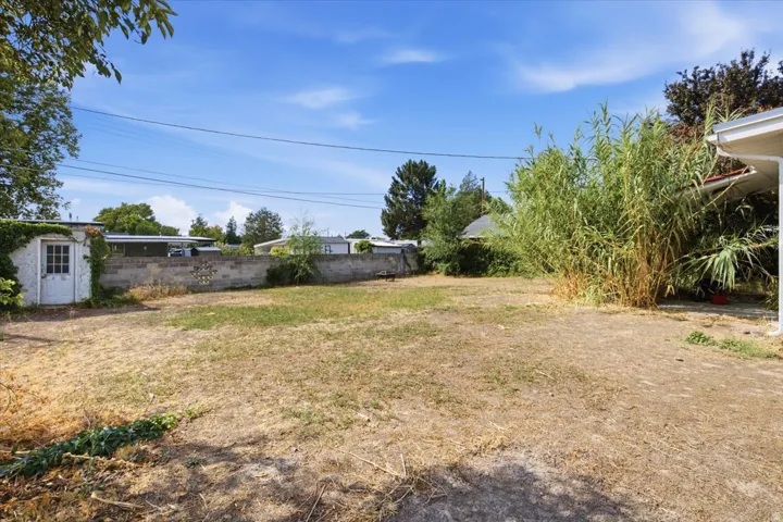 Expansive rear yard featuring an accessory structure with a paneled door and a concrete block perimeter wall