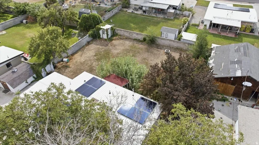 Rooftop solar panels, expansive rear yard, mature trees, concrete perimeter wall, and a detached outbuilding