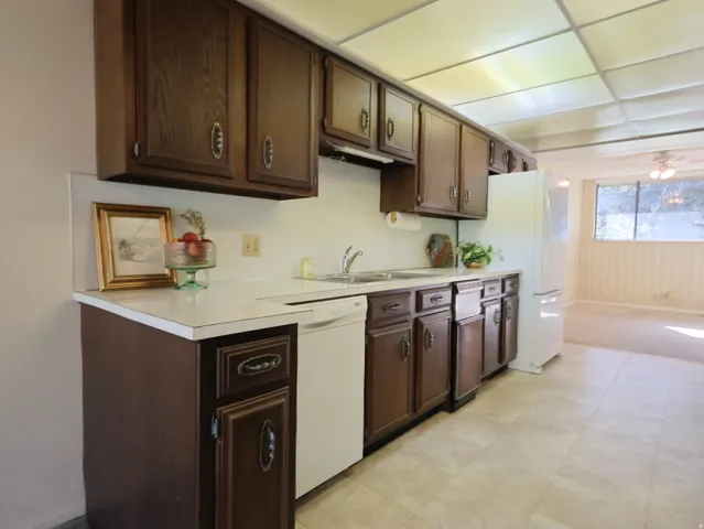 Kitchen featuring wood-finish cabinetry, white countertops, a double basin sink, and tile flooring