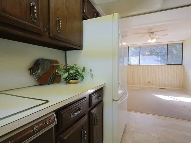 Kitchen featuring wood cabinetry with decorative hardware, white countertops, and a white refrigerator